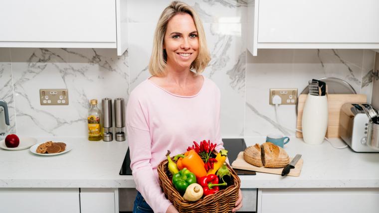 Beautiful News - Tessa Clarke smiling and holding a basket of fruit and vegetables