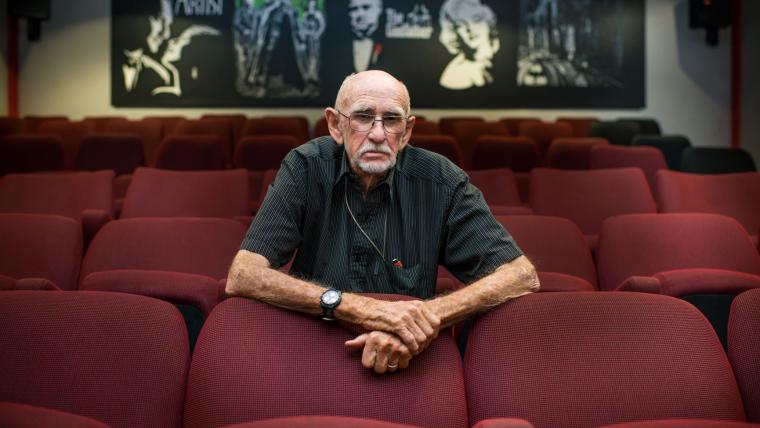 Old white man sitting in the cinema.