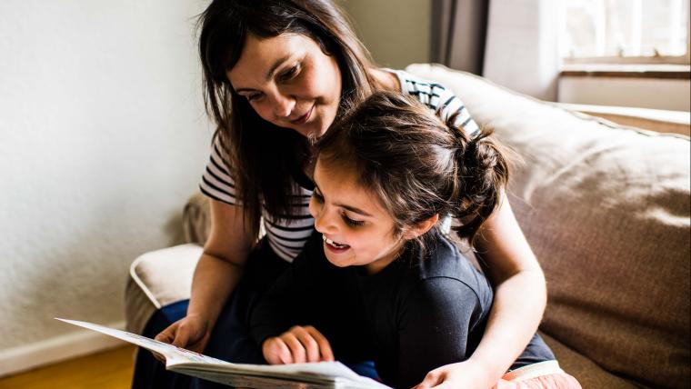 Mother reading book with daughter