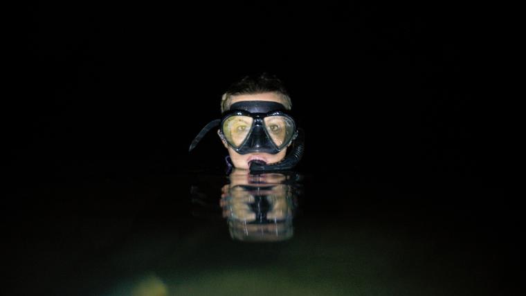 Woman in the sea at night wearing a snorkeling mask
