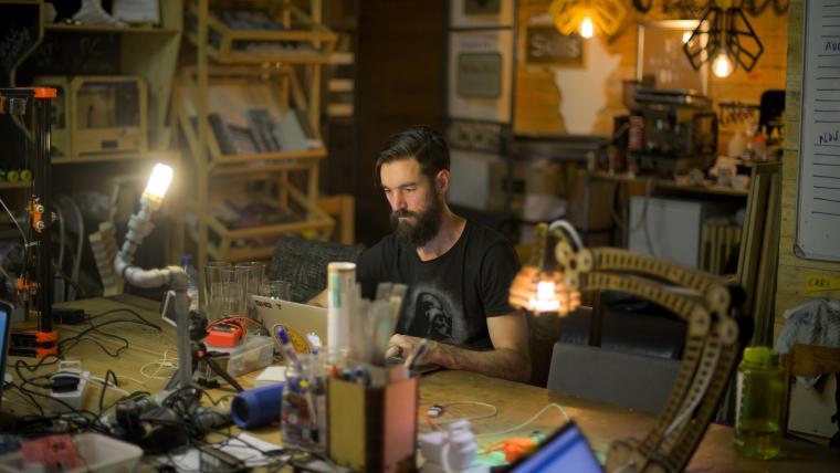 Man sits at a desk surrounded by different lamps