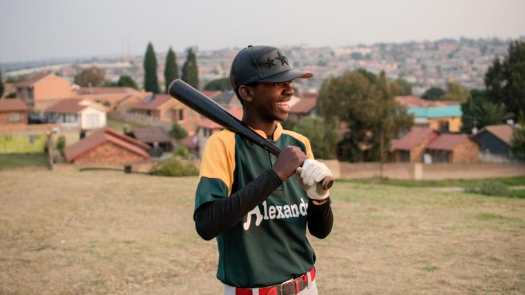 Boy smiling holding a baseball bat