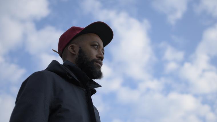 Man wearing a cap looks off into the distance