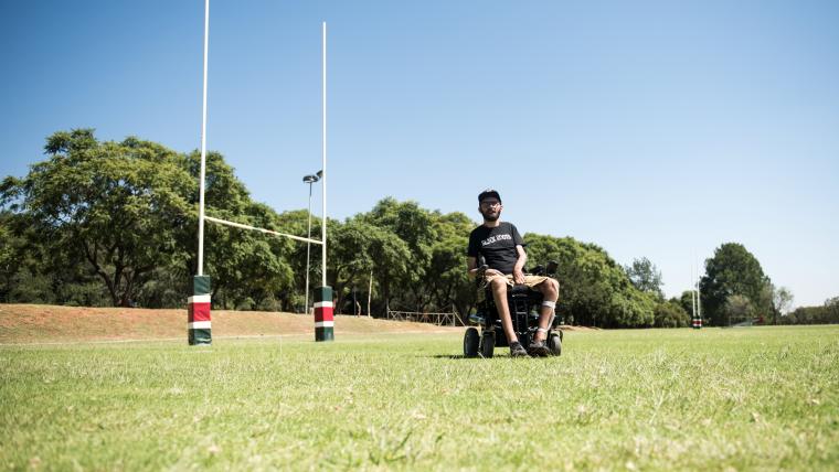 Man sits in a wheelchair on a rugby field