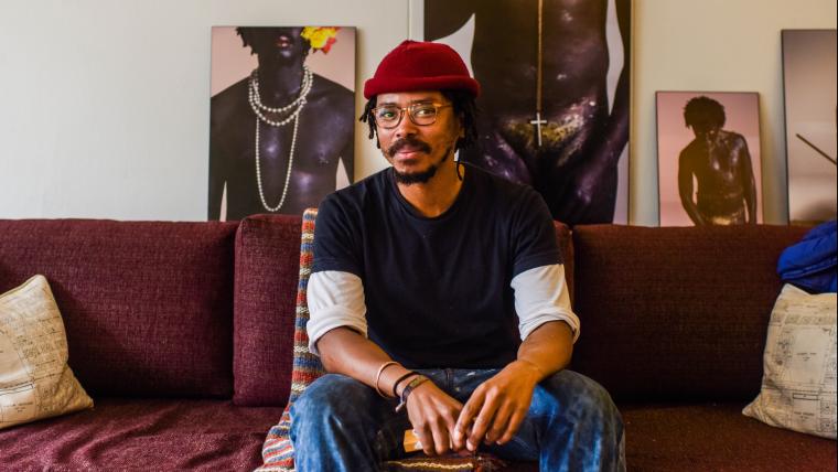 Man sitting on couch with artwork behind him