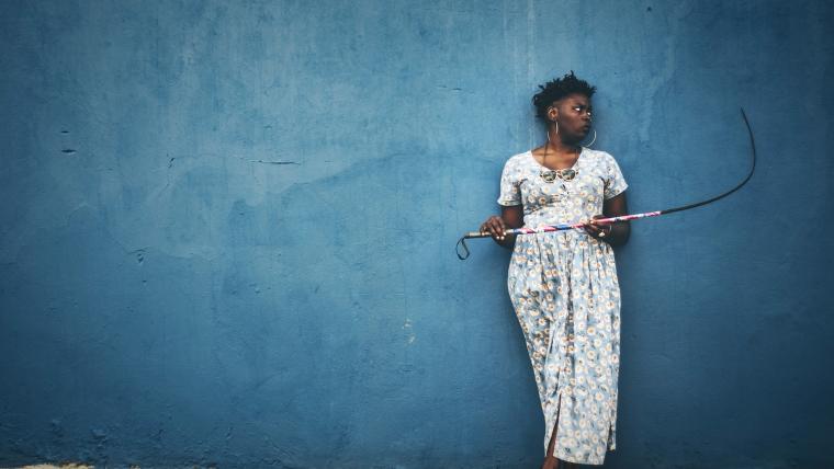 African woman holding a stick looking off to the side