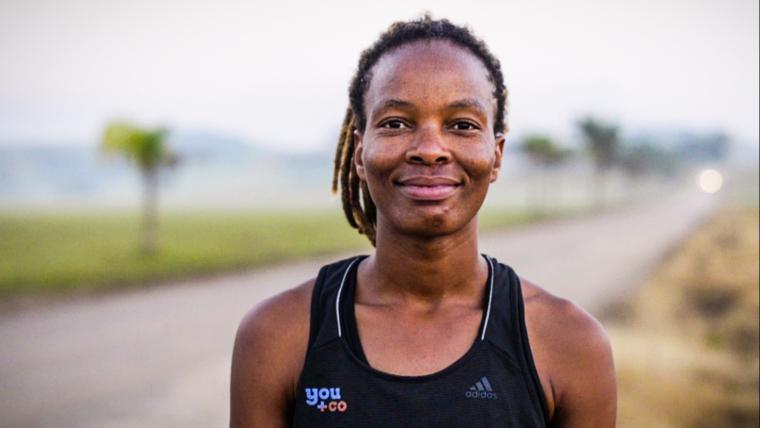 Black woman wearing running clothes is smiling at the camera
